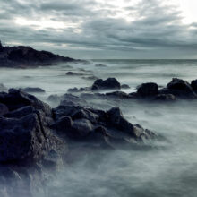 photo qui représente des rochers avec les vagues.